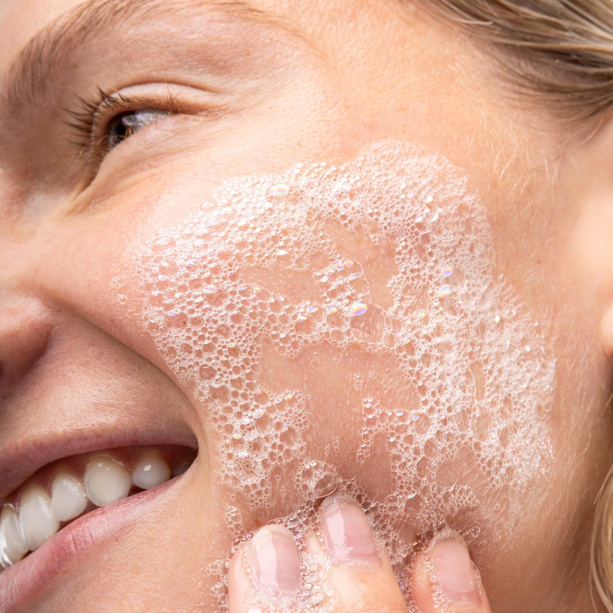 Close-up of a person applying The Body Shop Tea Tree Facial Wash to their face.