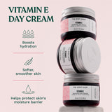 Three jars of The Body Shop Vitamin E Day Cream on a light pink background with text about product benefits. Boosts hydration. Softer, smoother skin. Helps protect skin's moisture barrier.