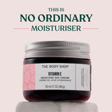 The Body Shop Vitamin E Moisture Day Cream jar on a light pink background with text 'This is No Ordinary Moisturiser'.